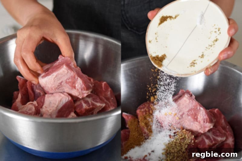 Seasoning pork shoulder cubes in a large bowl with an aromatic blend of salt, cumin, red pepper flakes, and dried oregano.