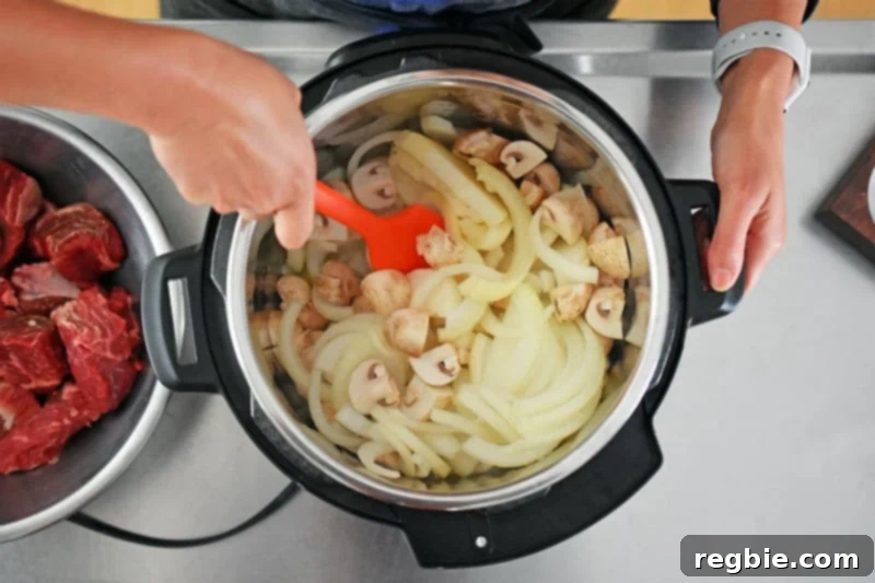 An overhead shot of someone mixing mushrooms and onions in an Instant Pot