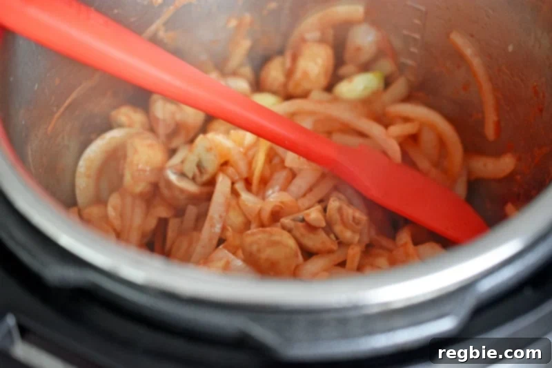Tomato paste and garlic are stirred into the vegetables in the Instant Pot