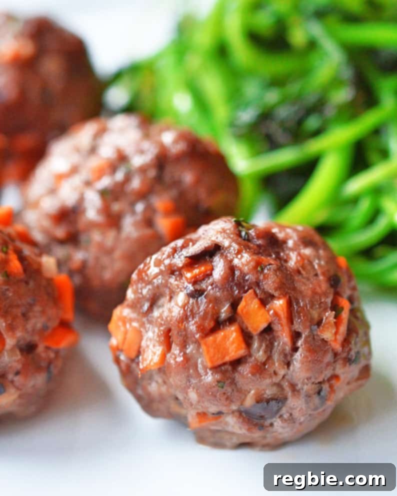 Sticky Glazed Asian Meatballs 2 A close up shot of perfectly cooked Asian Meatballs garnished with fresh cilantro, resting alongside a vibrant pile of stir-fried green vegetables, showcasing a delicious and healthy meal.
