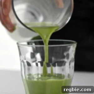 Someone pouring Cold Matcha Latte into a clear glass.