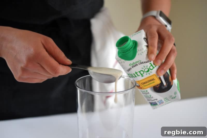 Refreshingly Cool Whole30 Dairy-Free Iced Matcha Latte 6 Someone measuring out a non-dairy creamer to add to the blending cup for the Iced Matcha Latte.