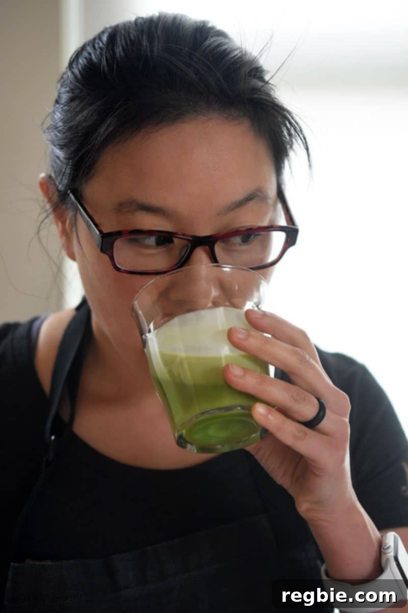 Refreshingly Cool Whole30 Dairy-Free Iced Matcha Latte 10 A smiling woman with glasses enjoys a tall glass of Iced Matcha Latte, held up near her face.