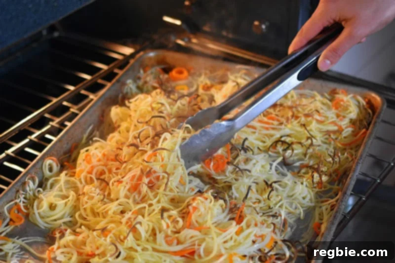 Crispy Swoodles being tossed by a pair of tongs as it cooks in the oven.