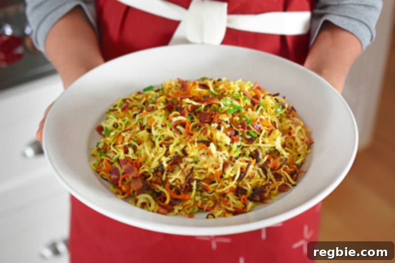 A shot of someone in a red apron holding a large plate of Crispy Swoodles With Bacon.