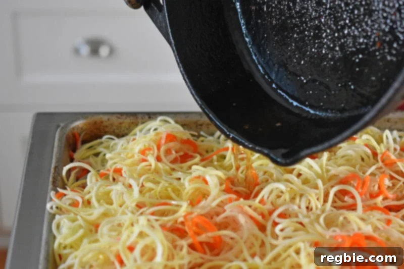 The reserved bacon grease is poured onto the salted spiralized vegetables.