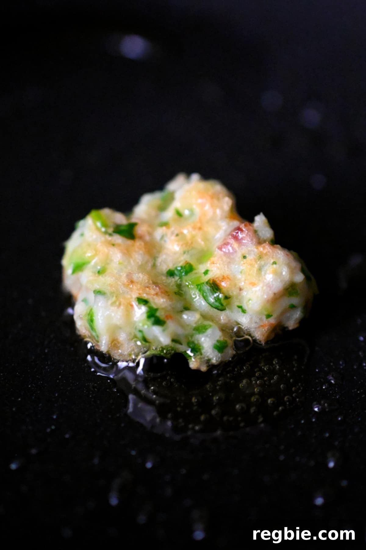 A spatula holding a portion of the final shrimp stuffing, showcasing its appealing sticky and chunky texture.