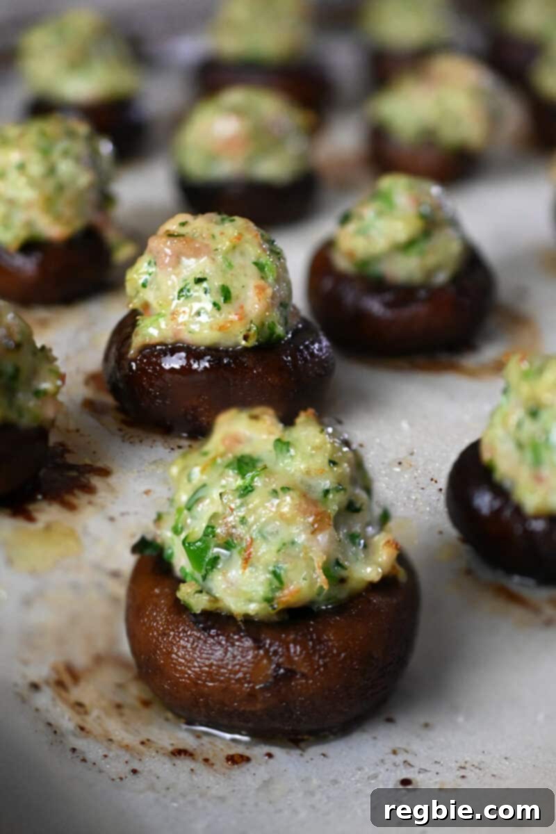 A captivating close-up of a tray of freshly baked, Chinese-inspired shrimp stuffed mushrooms, beautifully golden and steaming, resting on a parchment-lined baking tray.