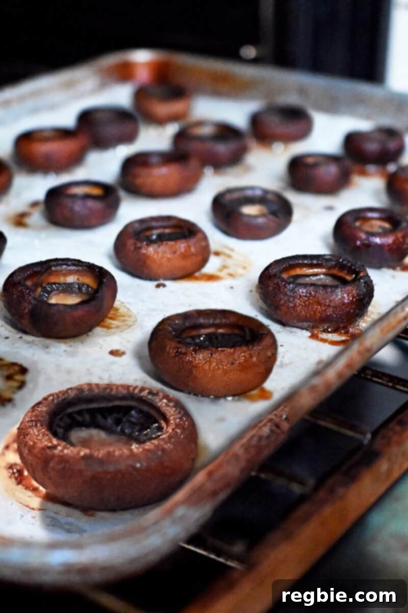 A tray of beautifully roasted cremini mushrooms, now gill-side up, with all excess moisture evaporated, ready for the next step.