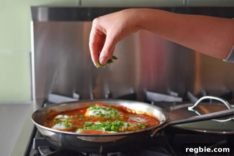 Quick Tomato Poached Cod One-Pan Meal 13 Finely minced fresh herbs, predominantly vibrant Italian parsley, are being generously sprinkled over the hot Poached Cod in Tomato Sauce, adding a burst of color and fresh aroma just before serving.
