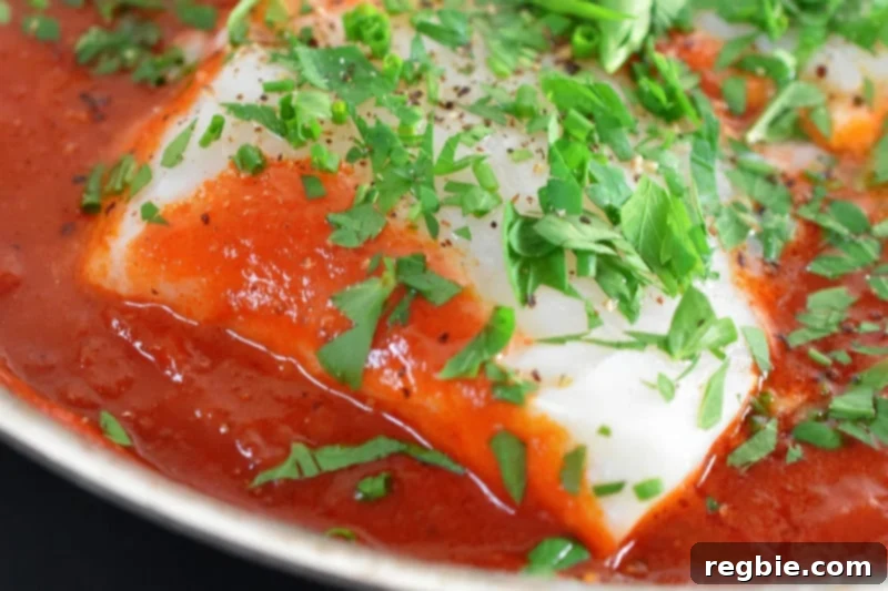Quick Tomato Poached Cod One-Pan Meal 3 A vibrant, close-up shot of tender, flaky poached cod fillets beautifully nestled within a rich, simmering tomato sauce. The steam rising gently suggests the dish is fresh off the stove and ready to be enjoyed.