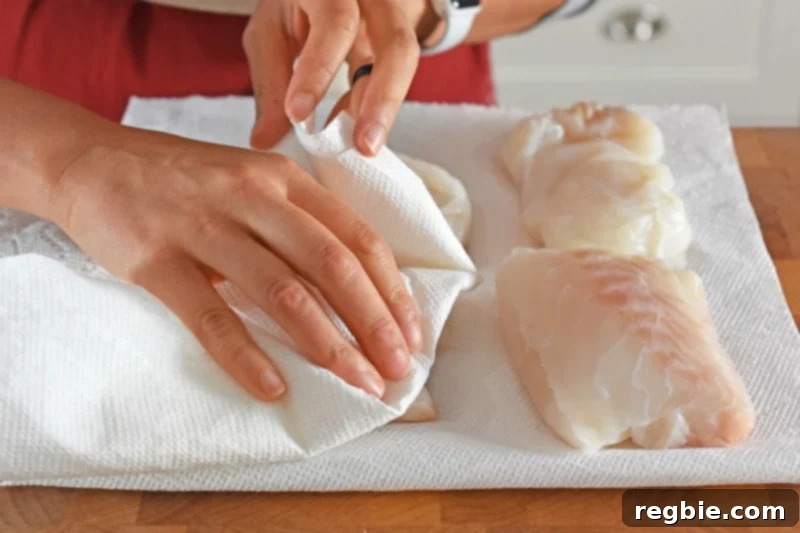 Quick Tomato Poached Cod One-Pan Meal 5 Boneless, skinless cod fillets are meticulously patted dry between two fresh pieces of paper towel on a cutting board. This essential step removes excess moisture, guaranteeing superior texture and flavor in the cooked fish.