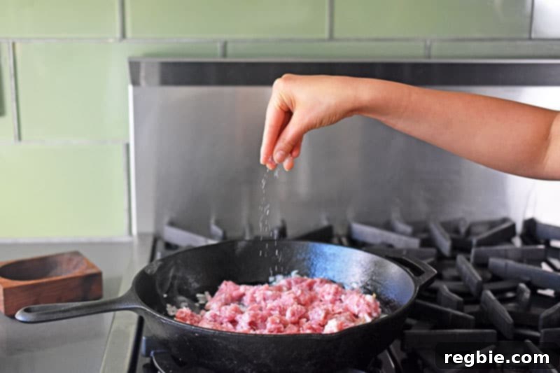 Seasoning the ground pork with a sprinkle of salt.