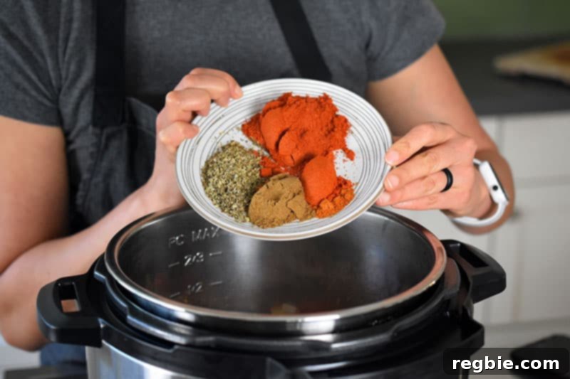 A closeup of a woman adding a plate filled with chili powder, oregano, cumin, and cayenne pepper into an open Instant Pot.