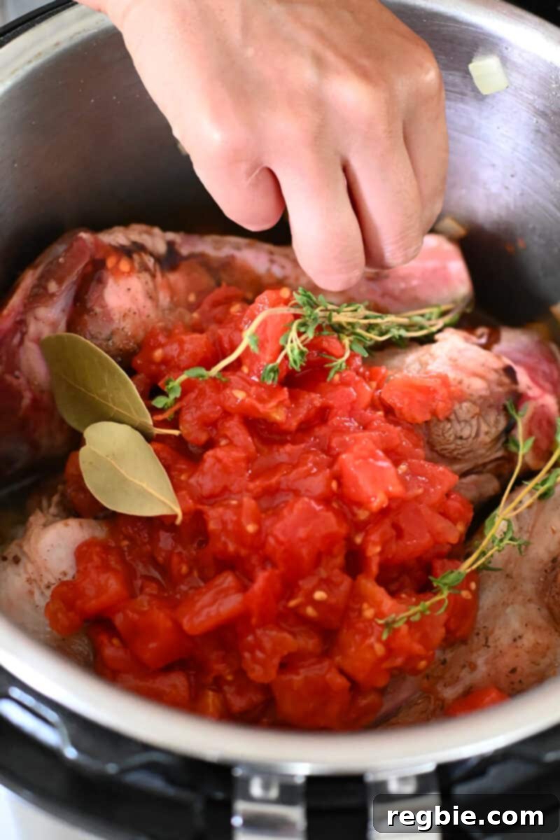 Adding dried bay leaves and fresh herbs to an Instant Pot filled with lamb shanks.