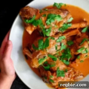A hand holding a white plate with Instant Pot lamb chops ready to eat.
