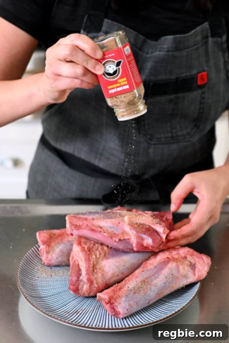Sprinkling a bottle of Nom Nom Paleo's Magic Mushroom Powder on a platter of raw lamb shanks.