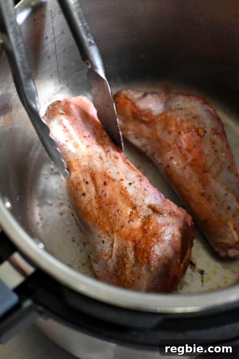 Closeup of a lamb shank being seared in an Instant Pot.