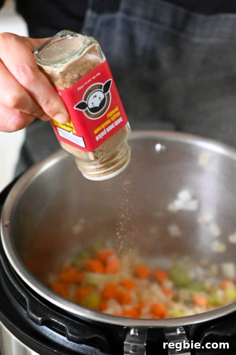 Seasoning chopped vegetables in an open Instant Pot with a bottle of Magic Mushroom Powder.