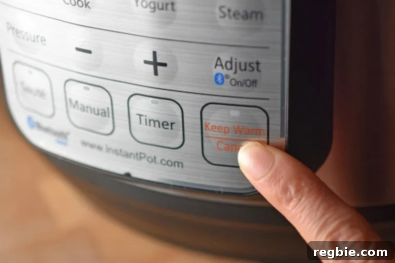 A finger pressing the 'Keep Warm / Cancel' button on an Instant Pot, signaling the end of the sauté phase and transition to pressure cooking.