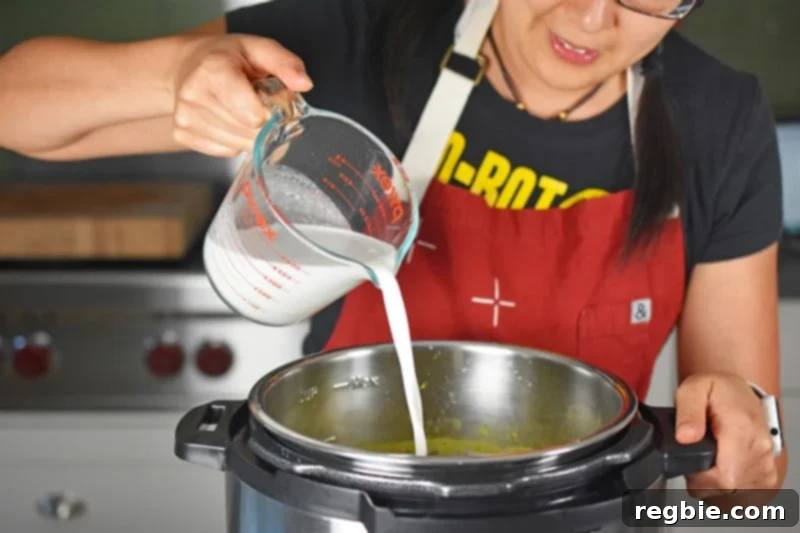A woman pouring rich, full-fat coconut milk into the dairy-free Instant Pot Curried Cream of Broccoli Soup, adding the final touch of creaminess.