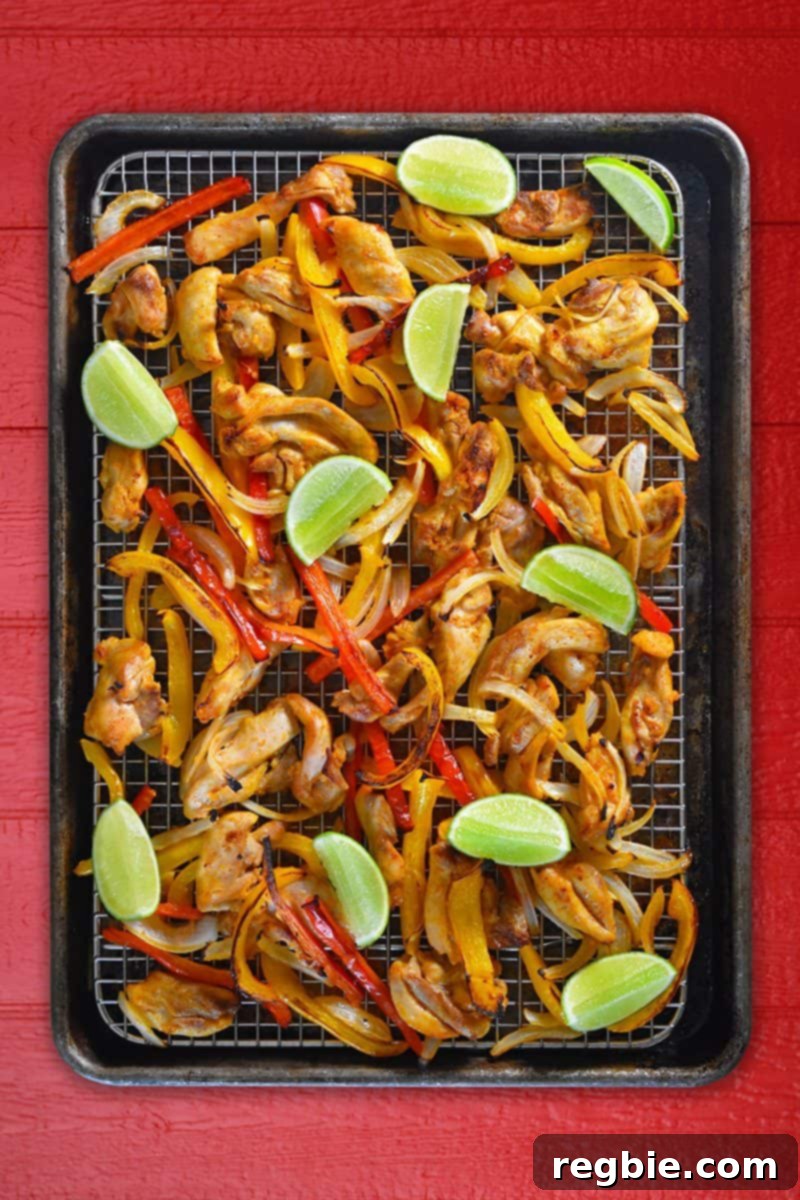 An overhead shot of perfectly roasted Sheet Pan Chicken Fajitas served with a side of creamy Avocado Crema.