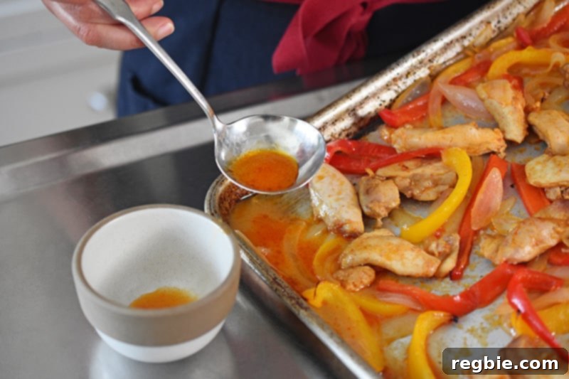 Someone scooping extra liquid from Sheet Pan Chicken Fajitas cooked without a wire rack, highlighting the issue of sogginess.