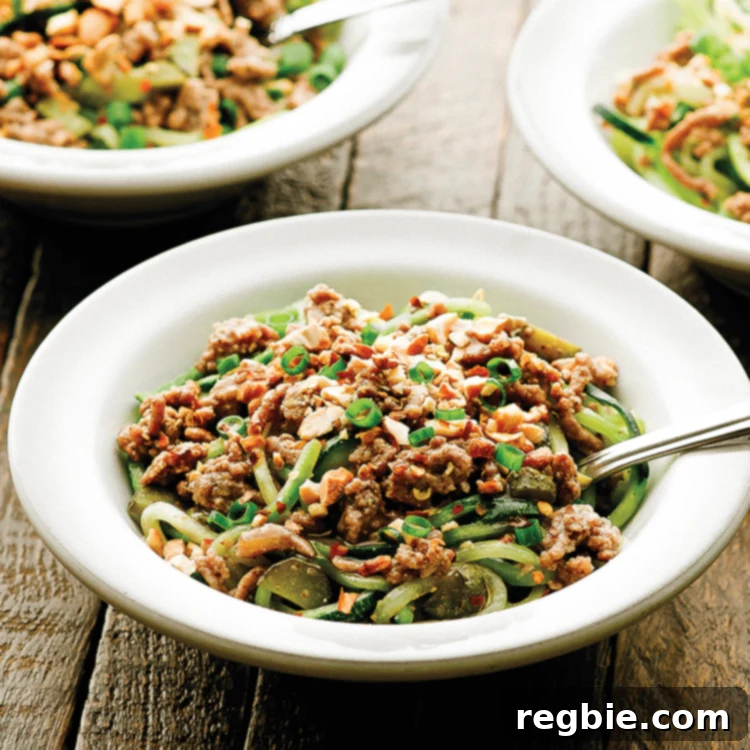 Keto Whole30 Spicy Dan Dan Noodles 6 Three bowls of paleo Dan Dan Noodles with spiralized zucchini, garnished with cashews and scallions.