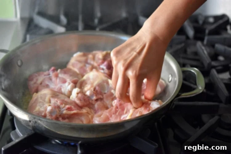 Golden-Crisp Cantonese Chicken Thighs 11 Pan-frying chicken thighs skin-side down in a stainless steel skillet.