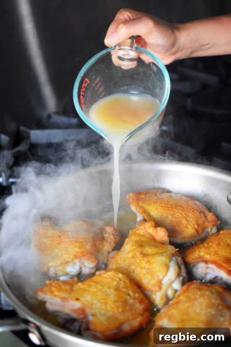 Golden-Crisp Cantonese Chicken Thighs 15 Pouring bone broth into a pan of Cantonese Crispy Chicken Thighs