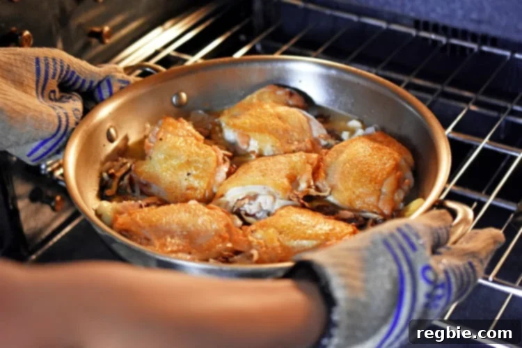 Golden-Crisp Cantonese Chicken Thighs 17 Placing the skillet of Cantonese Crispy Chicken Thighs into the oven.