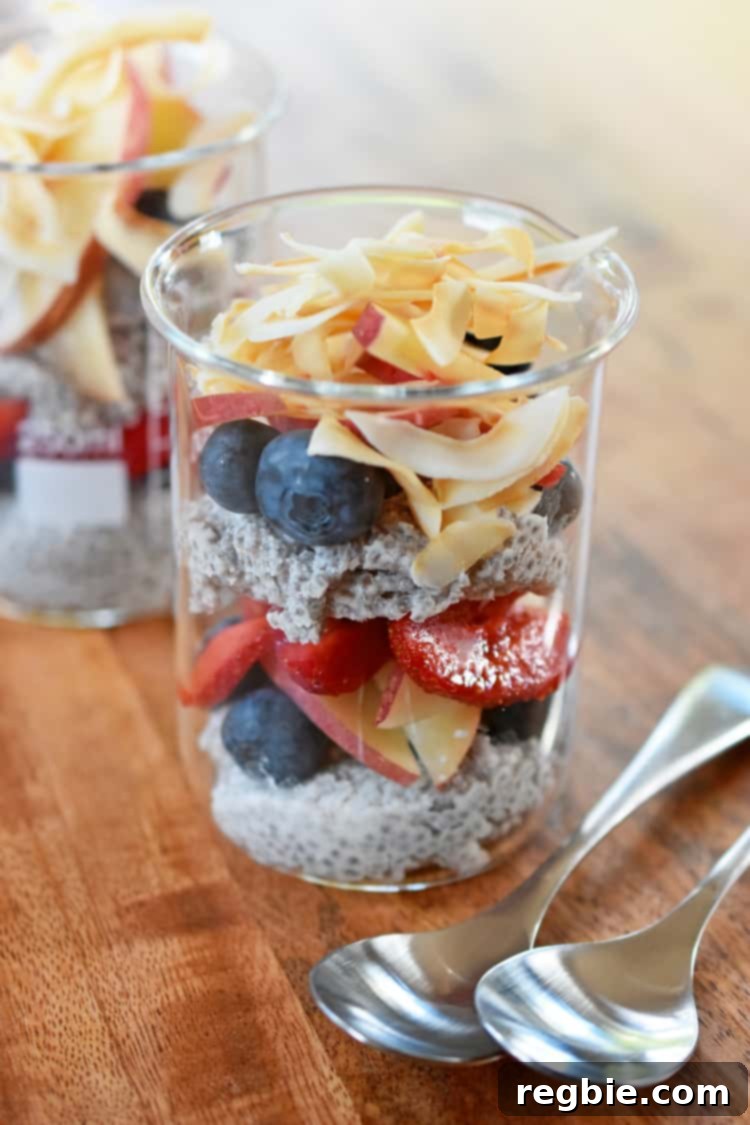 Two jars of coconut chia pudding topped with fresh fruit and toasted coconut.