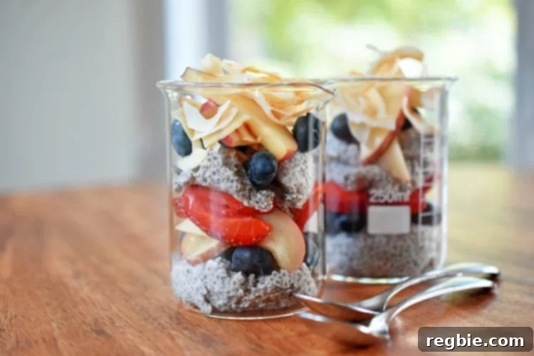 Two jars of coconut chia pudding layered with fresh fruit and toasted coconut,