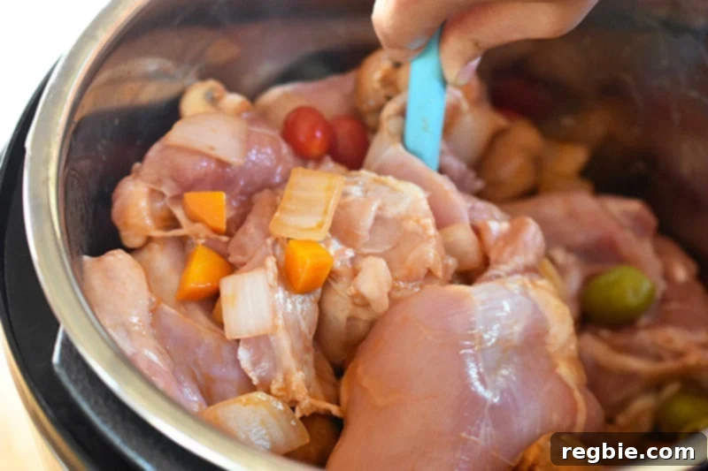 A person is stirring the raw ingredients for the Instant Pot Summer Italian Chicken stew before putting on the lid.