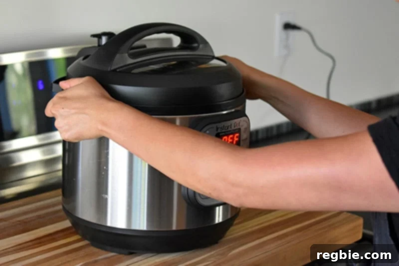 A person is putting an Instant Pot filled with Summer Italian Chicken stew under a vent, preparing for steam release.