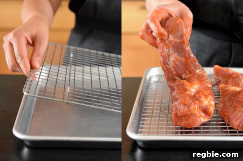 Marinated pork shoulder pieces arranged on a wire rack within a rimmed baking sheet, ready for the oven.