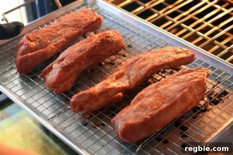 Paleo Char Siu pork pieces halfway through cooking, removed from the oven, showing initial browning.