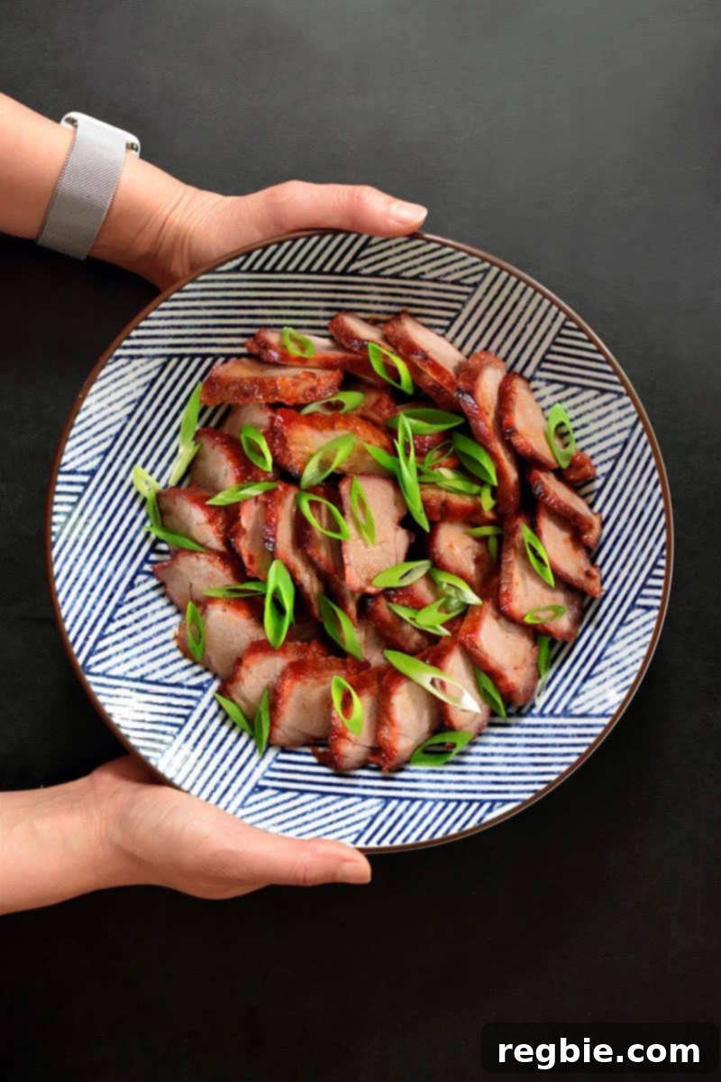 An overhead shot of Paleo Char Siu (Chinese BBQ Pork) served in a blue and white Japanese bowl, generously topped with fresh sliced scallions.