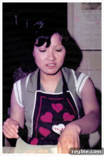 A heartwarming, grainy photo of the author's Chinese mother, wearing a heart-covered apron, busy cooking in the kitchen.