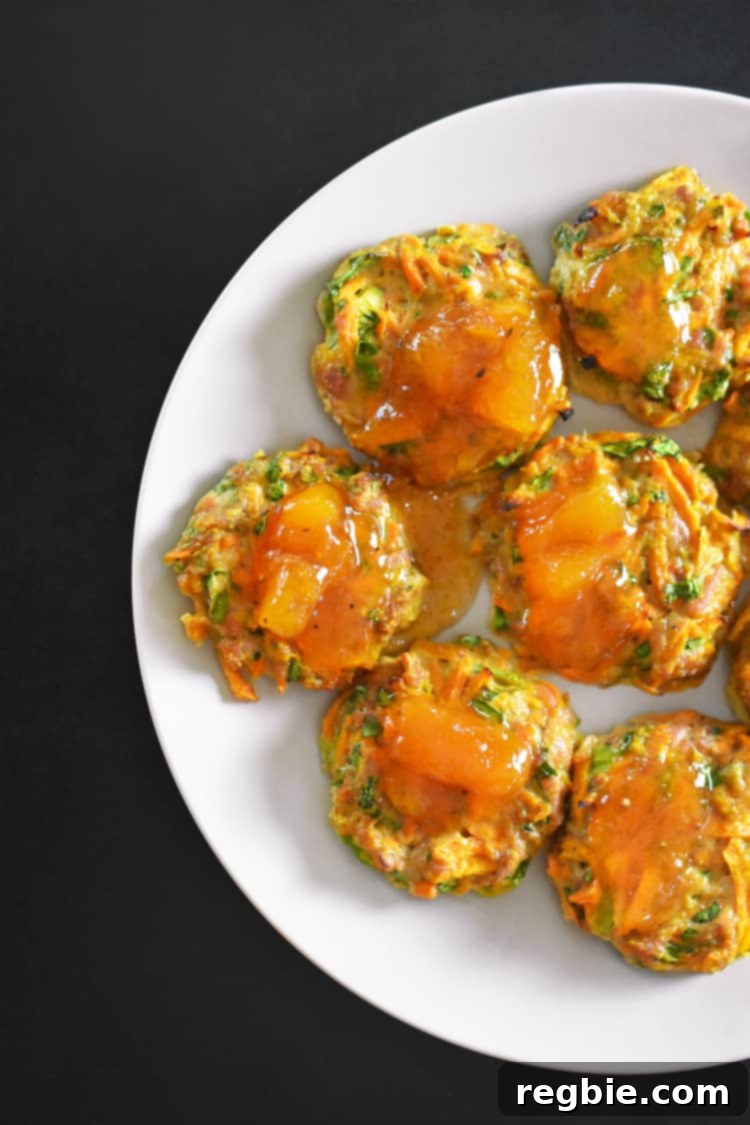 An overhead shot of vibrant, portable Whole30-friendly Curry Turkey Bites neatly arranged on a platter, accompanied by a small bowl of glistening Apricot Ginger Sauce, ready for serving.