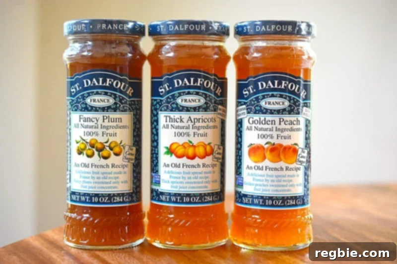Three jars of St. Dalfour brand jam – plum, apricot, and peach – are displayed, highlighting compliant options for Whole30 recipes, all sweetened naturally with fruit juice.