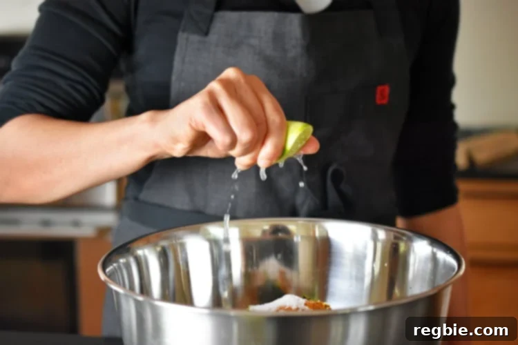 A stream of fresh lime juice is squeezed into a large mixing bowl, joining the raw ingredients for healthy Curry Turkey Bites to add a zesty, bright flavor.