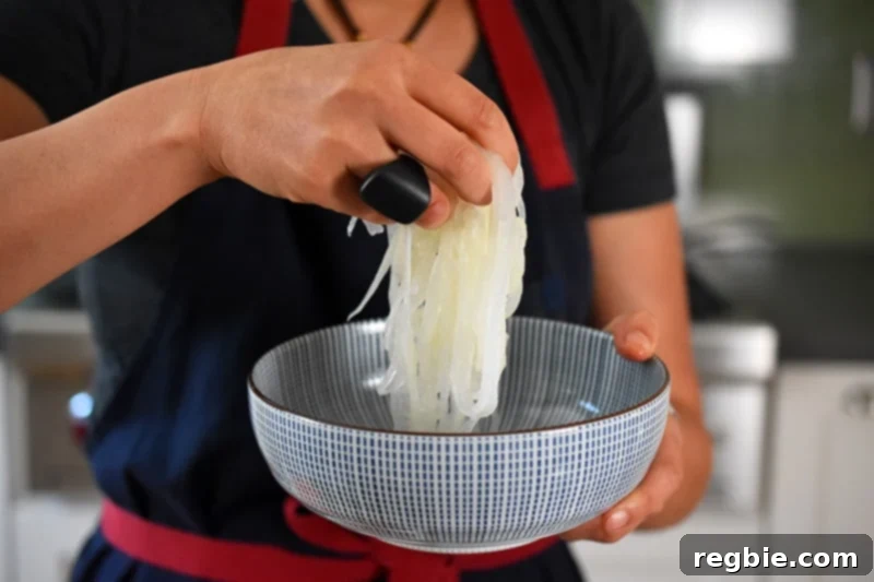 Someone carefully placing the chilled daikon noodles into a serving bowl.