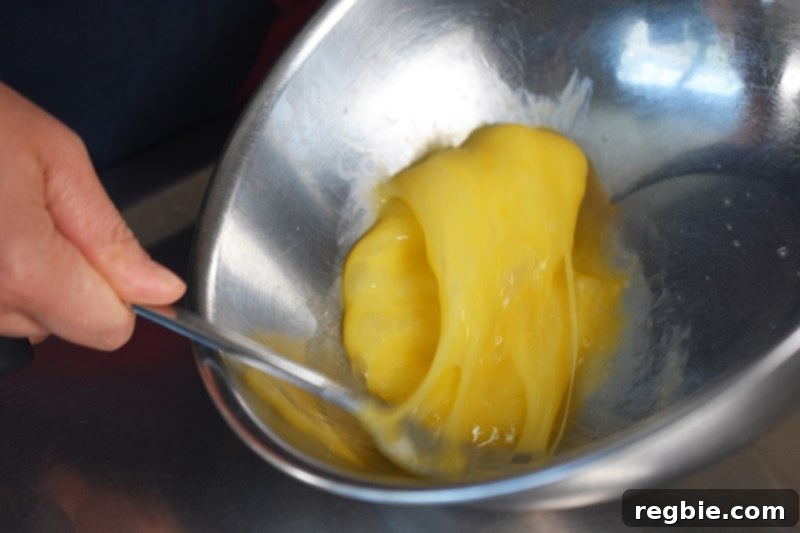 Someone beating eggs vigorously in a metal bowl with a fork to ensure a smooth omelet.