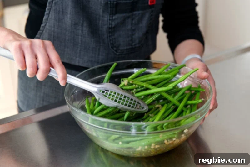 Crisp Lemon-Garlic Roasted Green Beans 5 Someone tossing green beans in a Whole30 and keto-friendly lemon and garlic marinade.
