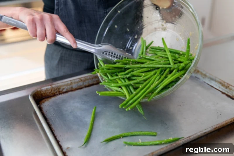 Crisp Lemon-Garlic Roasted Green Beans 6 Transferring the marinated green beans to a rimmed baking sheet with a pair of tongs.