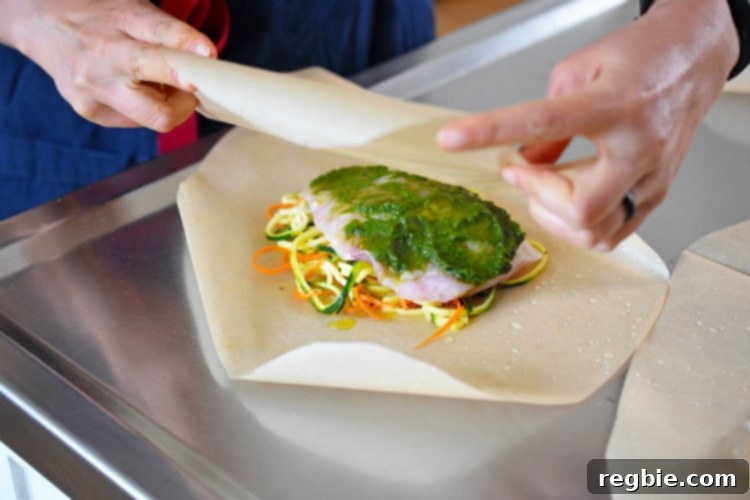 Wrapping up Fiona’s Phenomenal Fish Packets by crimping the edges of the parchment paper hearts.