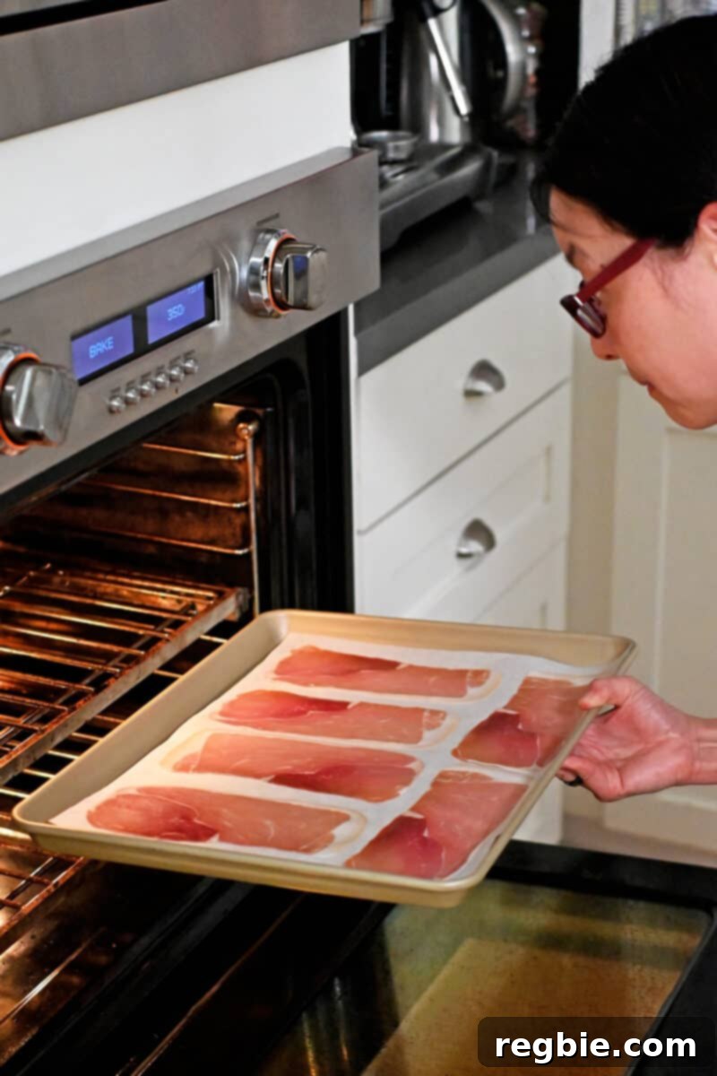 Golden Prosciutto Snaps 6 An Asian woman in glasses is placing a rimmed baking sheet with prosciutto slices into the oven,