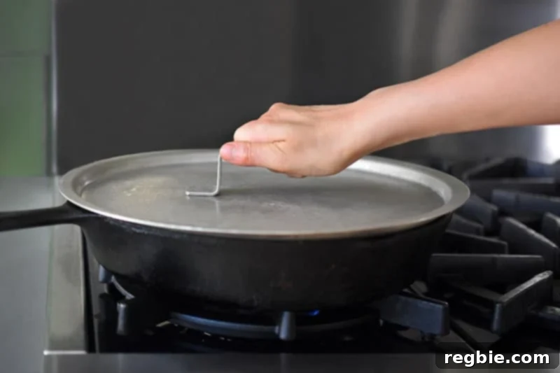 A pan containing the kimchi cauliflower fried rice mixture being covered with a lid to allow the cauliflower to steam and soften.
