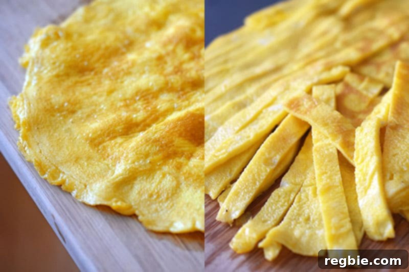 A golden, cooked egg omelet neatly sliced into thin strips on a wooden cutting board, ready to be added to the fried rice.